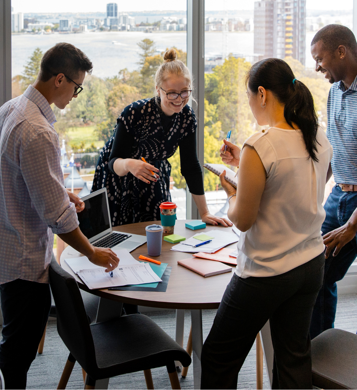 Diverse team collaborating around table in modern office with city view